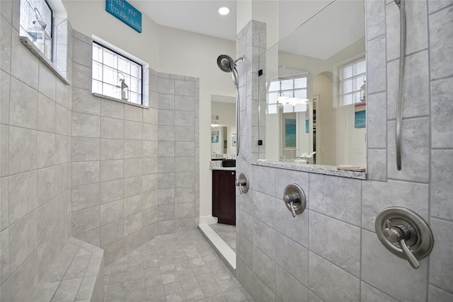 bathroom with a tile shower, vanity, and a wealth of natural light