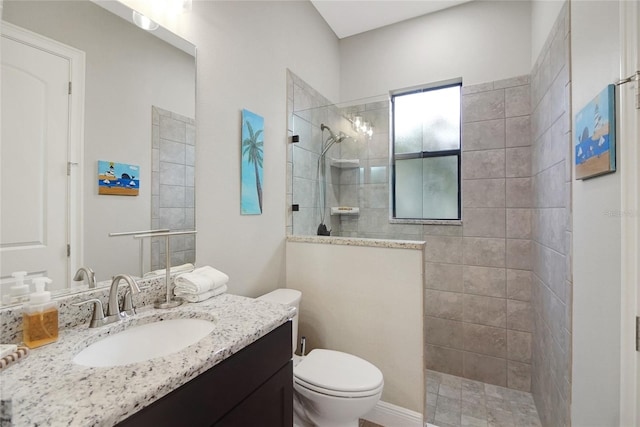 bathroom featuring toilet, vanity, and tiled shower