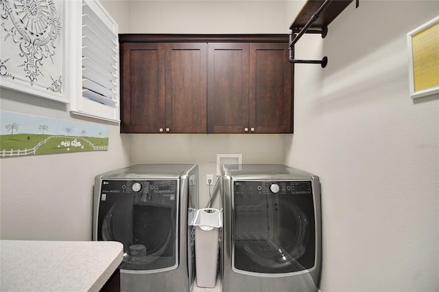 clothes washing area with washer and clothes dryer and cabinets