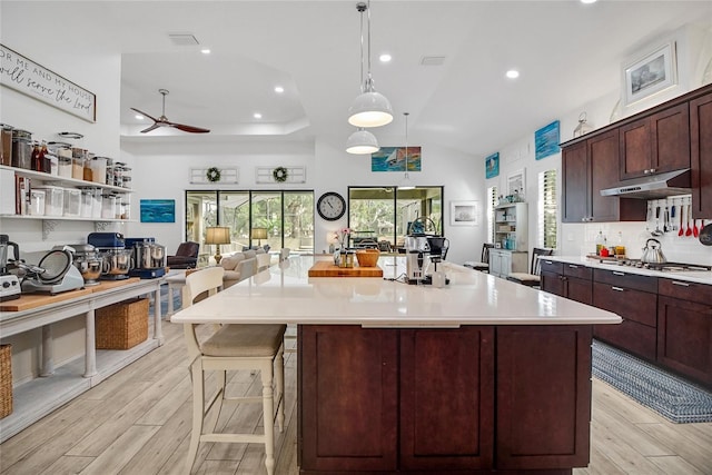 kitchen with a large island, ceiling fan, hanging light fixtures, stainless steel gas stovetop, and light wood-type flooring