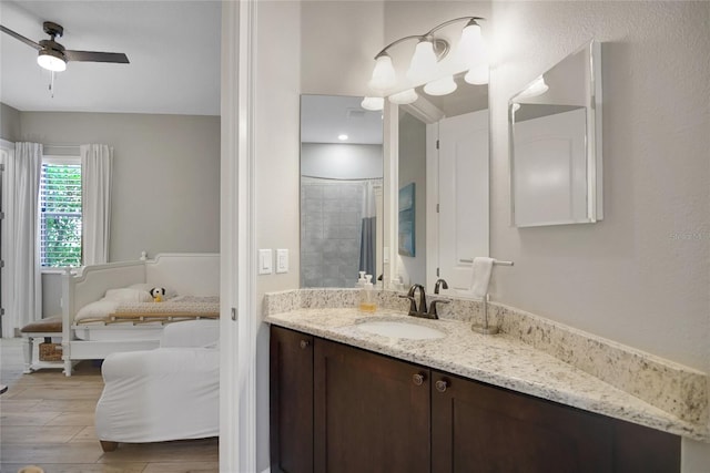 bathroom featuring ceiling fan, hardwood / wood-style floors, vanity, and tiled shower