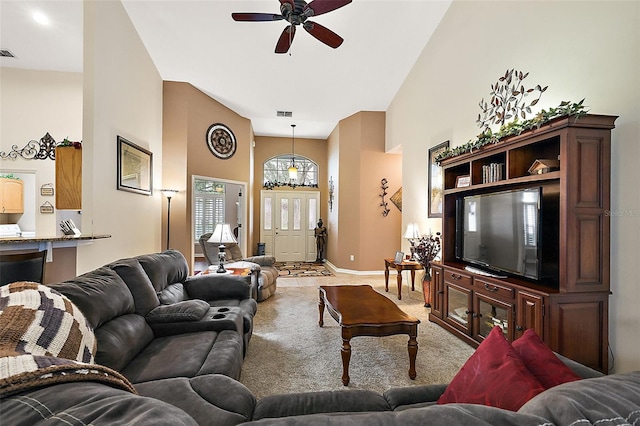 carpeted living room with ceiling fan and a high ceiling