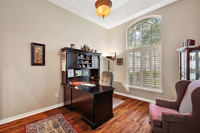 home office featuring dark hardwood / wood-style flooring and a towering ceiling