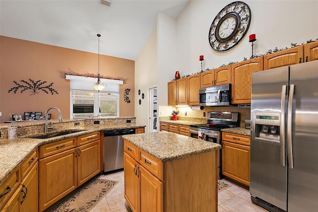 kitchen featuring a center island, sink, light stone countertops, pendant lighting, and appliances with stainless steel finishes