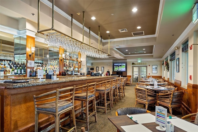 bar with carpet, crown molding, a tray ceiling, and stone countertops