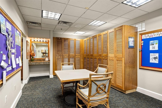 carpeted dining room with a paneled ceiling