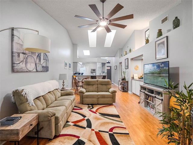 living room with high vaulted ceiling, light hardwood / wood-style floors, a textured ceiling, and ceiling fan