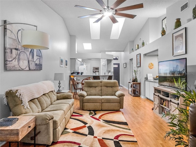 living room with ceiling fan, a textured ceiling, light wood-type flooring, and high vaulted ceiling