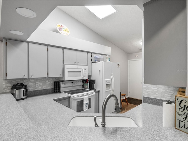 kitchen with tasteful backsplash, a textured ceiling, sink, vaulted ceiling, and white appliances