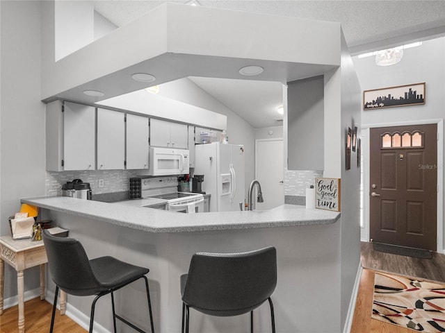 kitchen with hardwood / wood-style floors, tasteful backsplash, and white appliances