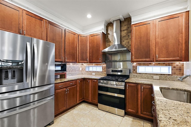 kitchen with light stone counters, wall chimney exhaust hood, stainless steel appliances, crown molding, and sink