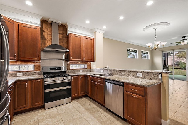 kitchen with light stone countertops, sink, wall chimney exhaust hood, kitchen peninsula, and appliances with stainless steel finishes