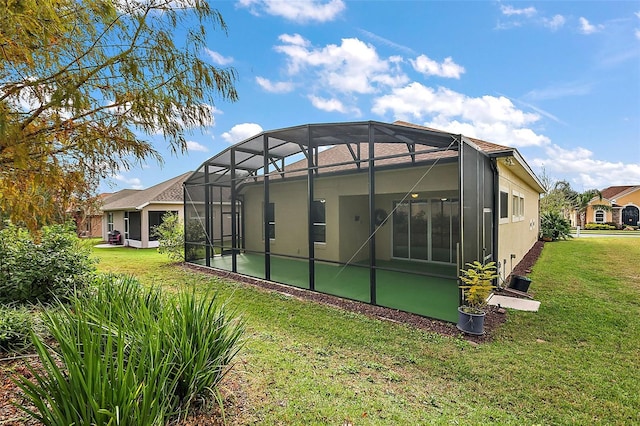 back of house featuring glass enclosure and a lawn