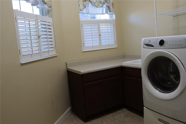 clothes washing area featuring washer / clothes dryer, light tile patterned floors, and a healthy amount of sunlight