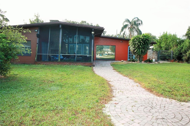 view of front facade with a front lawn and a sunroom