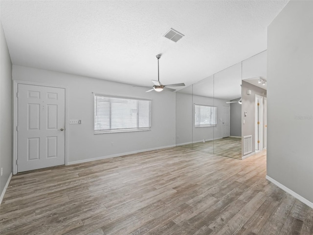 unfurnished living room with a textured ceiling, light hardwood / wood-style floors, and ceiling fan