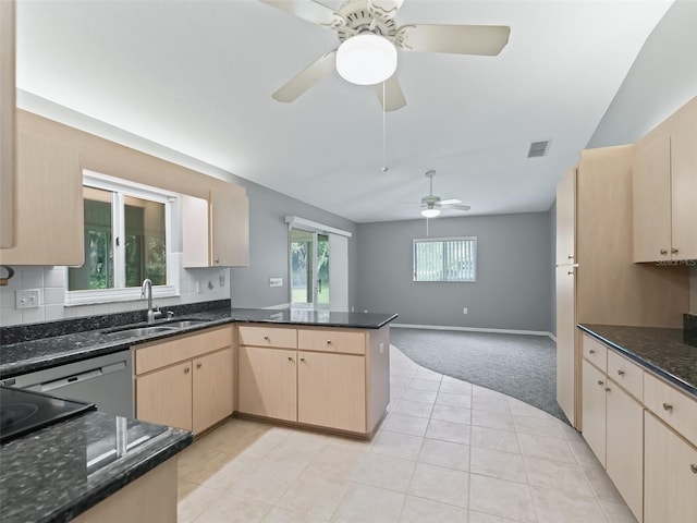 kitchen featuring light brown cabinetry, dark stone countertops, sink, and kitchen peninsula