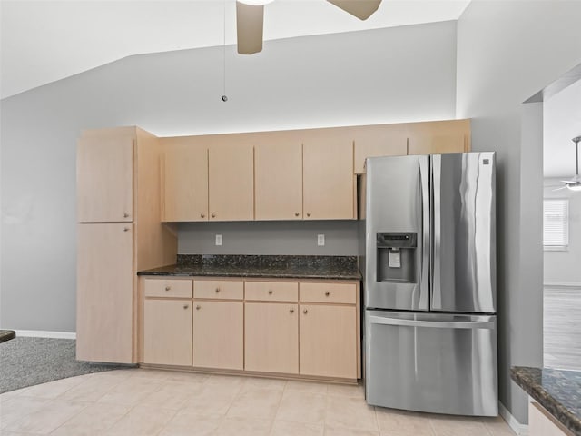 kitchen featuring light brown cabinetry, ceiling fan, dark stone countertops, lofted ceiling, and stainless steel fridge