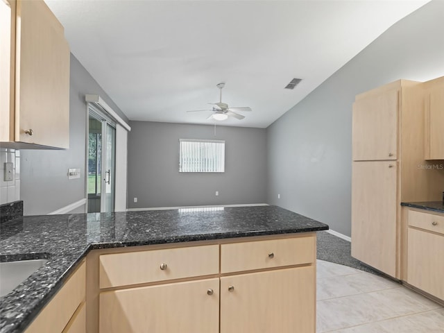 kitchen with dark stone counters, light brown cabinetry, and a healthy amount of sunlight