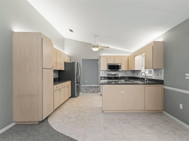 kitchen featuring light brown cabinets, stainless steel appliances, sink, and vaulted ceiling