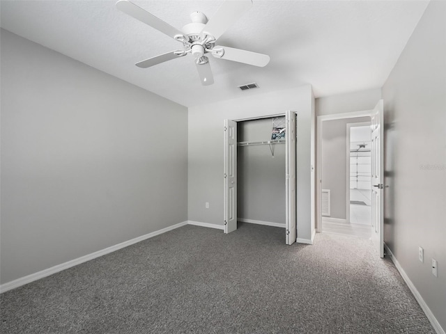 unfurnished bedroom with a closet, dark carpet, and ceiling fan