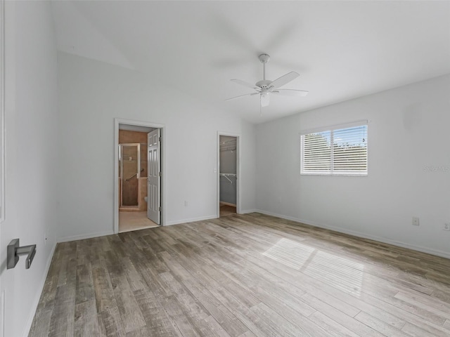 unfurnished bedroom with a closet, a spacious closet, ensuite bathroom, ceiling fan, and light hardwood / wood-style flooring