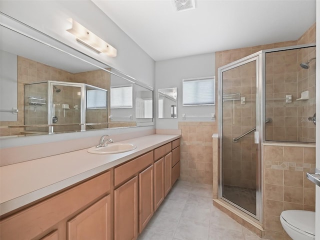 bathroom featuring a shower with door, vanity, toilet, and tile patterned flooring