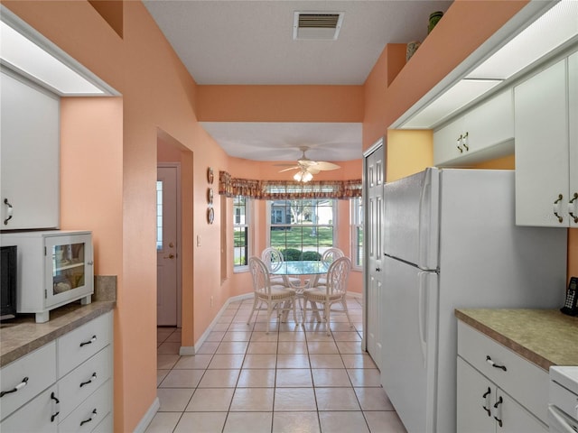 kitchen featuring light tile patterned flooring, ceiling fan, white cabinetry, and white fridge