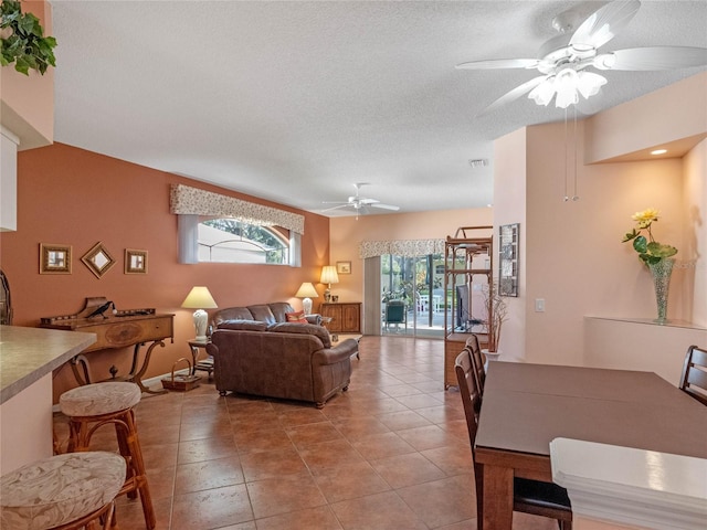 living room featuring a textured ceiling, light tile patterned floors, and ceiling fan