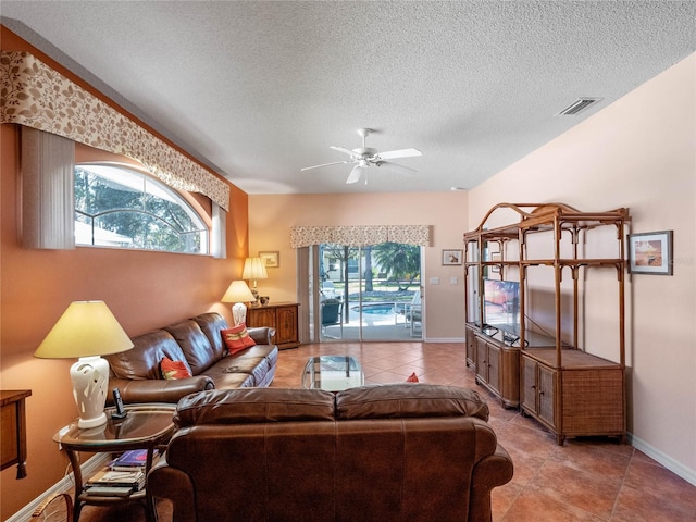 living room featuring a textured ceiling, light tile patterned floors, and ceiling fan