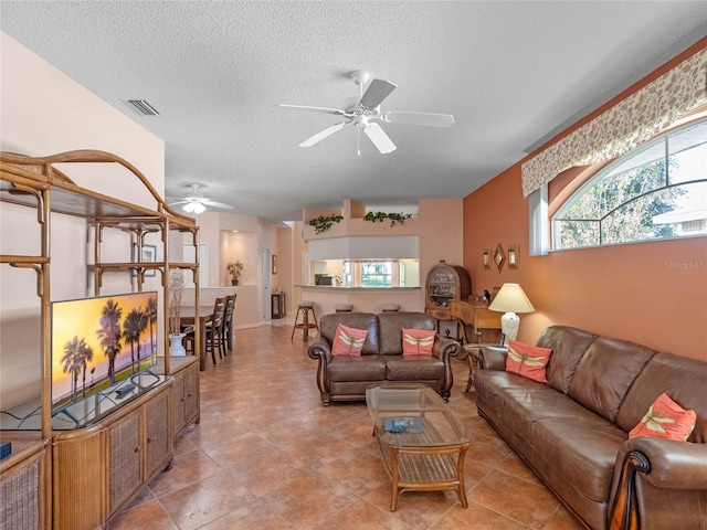 tiled living room with ceiling fan and a textured ceiling