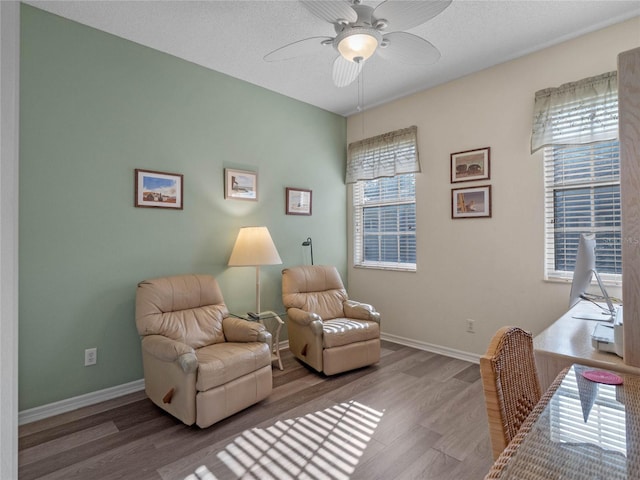 living area featuring ceiling fan, a wealth of natural light, wood-type flooring, and a textured ceiling