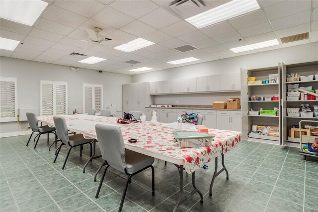 tiled dining room featuring a drop ceiling and ceiling fan