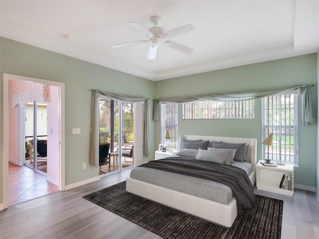 bedroom with ceiling fan, access to exterior, multiple windows, and light hardwood / wood-style flooring