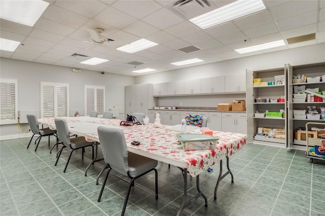 dining area with a drop ceiling and ceiling fan