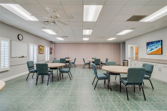 dining space with a drop ceiling and ceiling fan