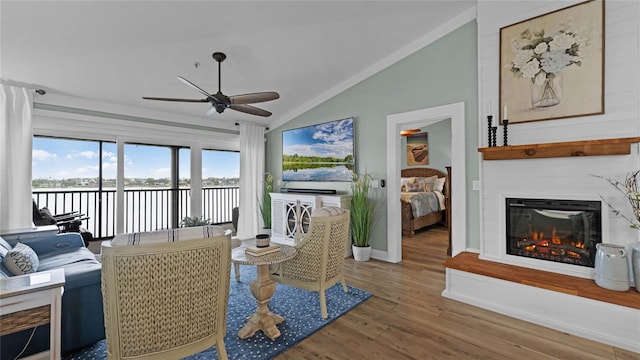 living room featuring ceiling fan, lofted ceiling, hardwood / wood-style flooring, and a large fireplace