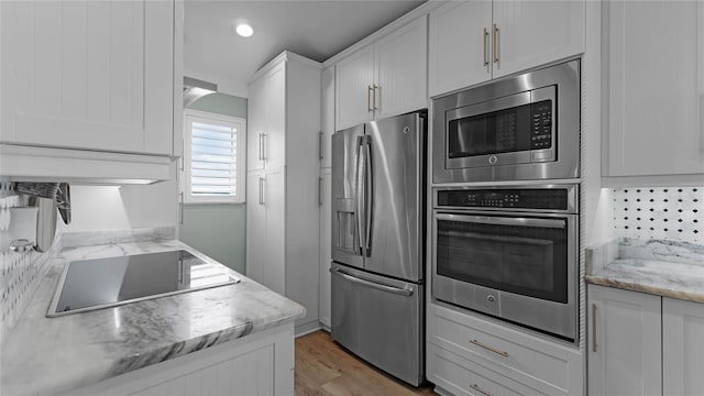 kitchen with white cabinetry, appliances with stainless steel finishes, backsplash, and light hardwood / wood-style flooring