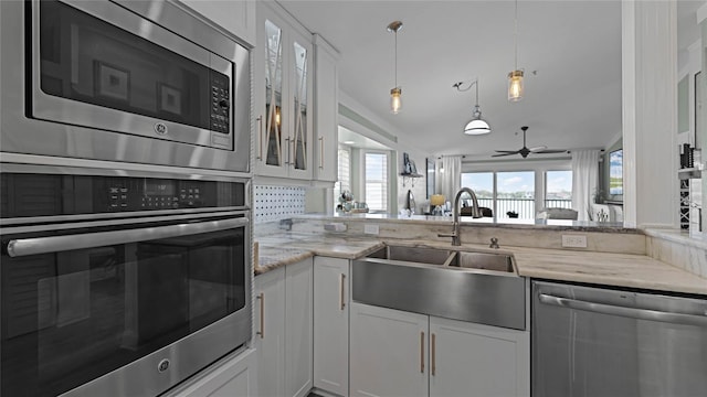 kitchen featuring white cabinetry, sink, appliances with stainless steel finishes, light stone countertops, and ceiling fan