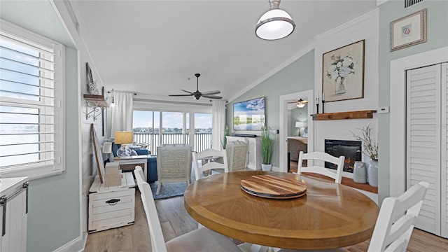 dining space featuring a wealth of natural light, a high end fireplace, light hardwood / wood-style flooring, and vaulted ceiling