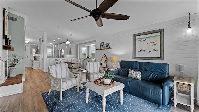 living room featuring wood walls, hardwood / wood-style flooring, and ceiling fan