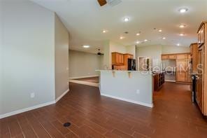 kitchen with a center island with sink, dark hardwood / wood-style floors, refrigerator, and a breakfast bar