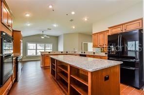 kitchen with black refrigerator, kitchen peninsula, hardwood / wood-style floors, a kitchen island, and lofted ceiling