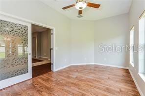 unfurnished room with ceiling fan, a healthy amount of sunlight, and wood-type flooring