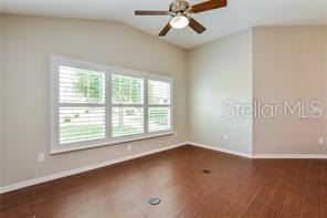 spare room with plenty of natural light, ceiling fan, and dark wood-type flooring