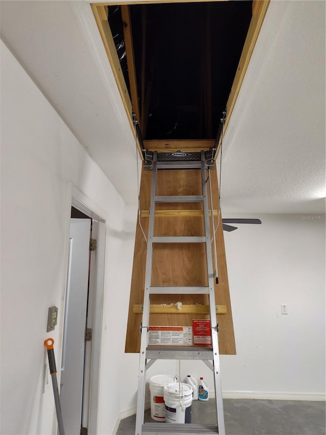 staircase with concrete floors and ceiling fan