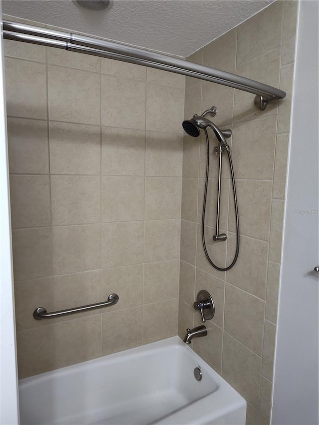 bathroom with a textured ceiling and tiled shower / bath