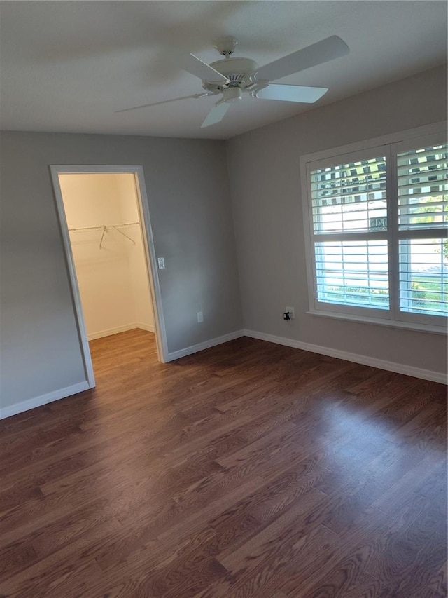 unfurnished bedroom with ceiling fan, dark hardwood / wood-style floors, a spacious closet, and a closet