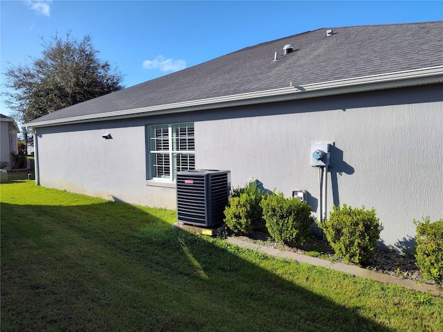 view of side of home with central air condition unit and a lawn