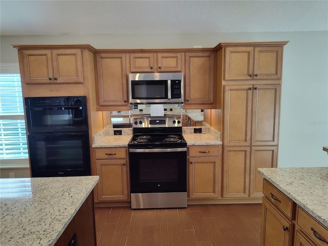 kitchen featuring light stone counters, stainless steel appliances, and light hardwood / wood-style flooring